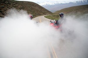 Two motorcyclist performing a burnout with lots of smoke.
